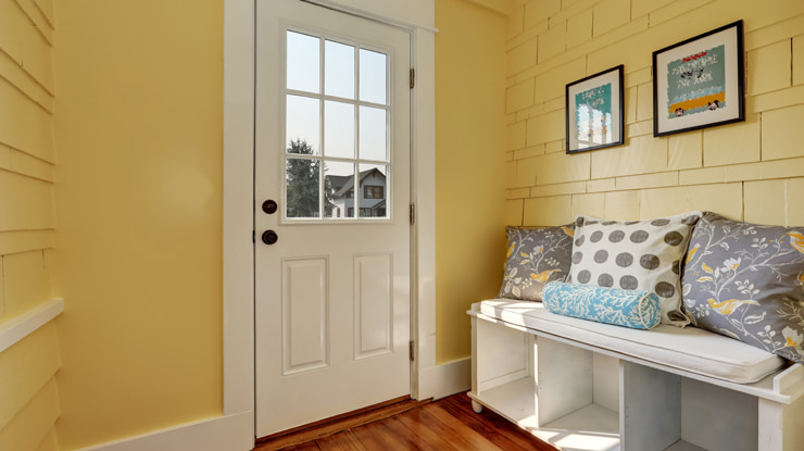 A room in yellow and white colors with a storage bench.