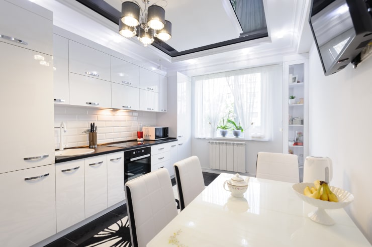  A kitchen in white colors with reflective surfaces.