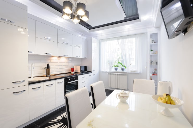 A kitchen in white colors with reflective surfaces.