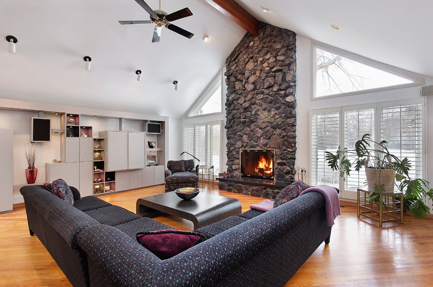 Spacious living room with a sofa and a fireplace decorated with stone veneer.