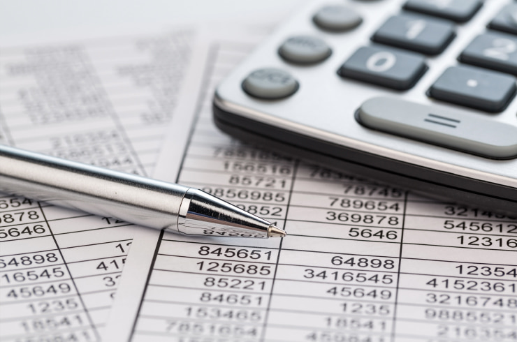 Calculator and a pen laying on sheets with data.