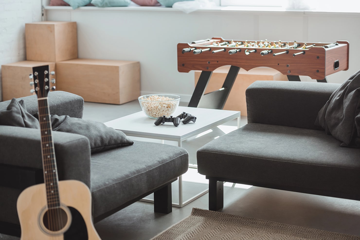 Game room with a foosball table, snacks, game controllers and a guitar.