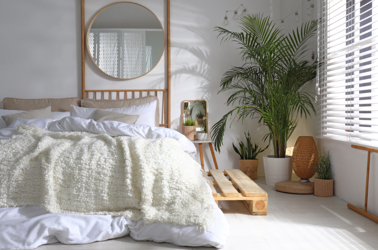 Cozy white bedroom with wooden decor and plants.