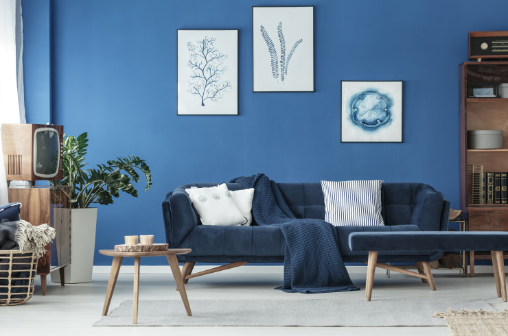 Living room in blue tones with three pieces of artwork hanging on the wall.