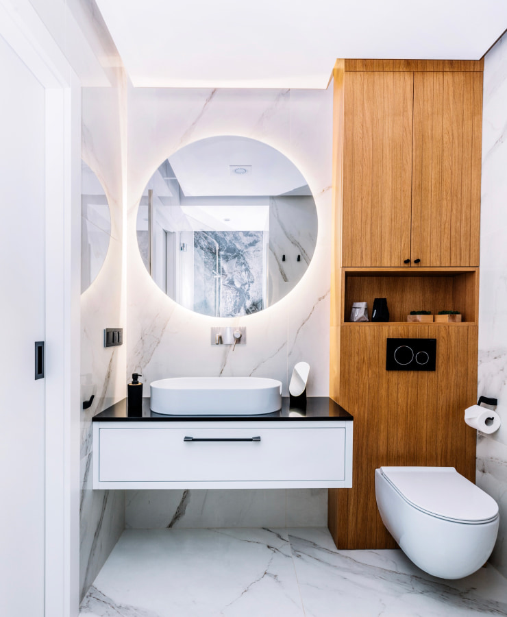 White marble bathroom with a tall wooden cabinet.