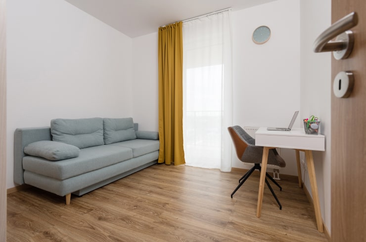 A bedroom with a sofa bed and a working area.