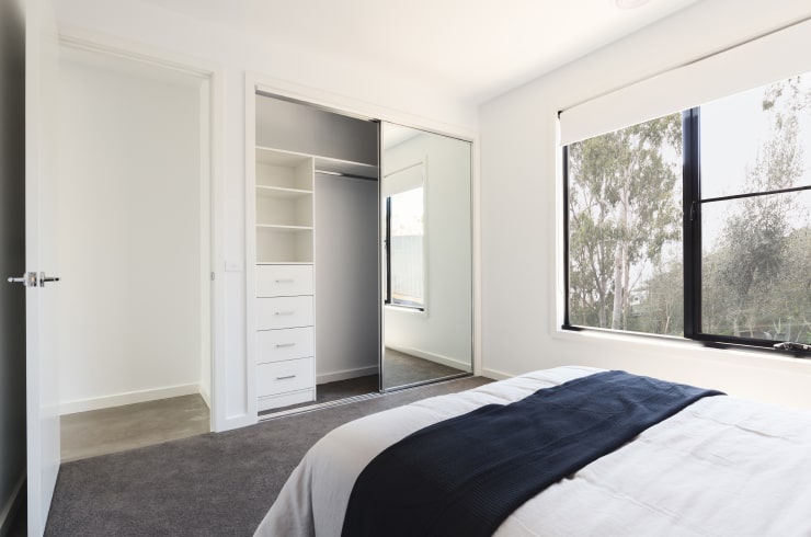 All white bedroom with a mirrored wardrobe.