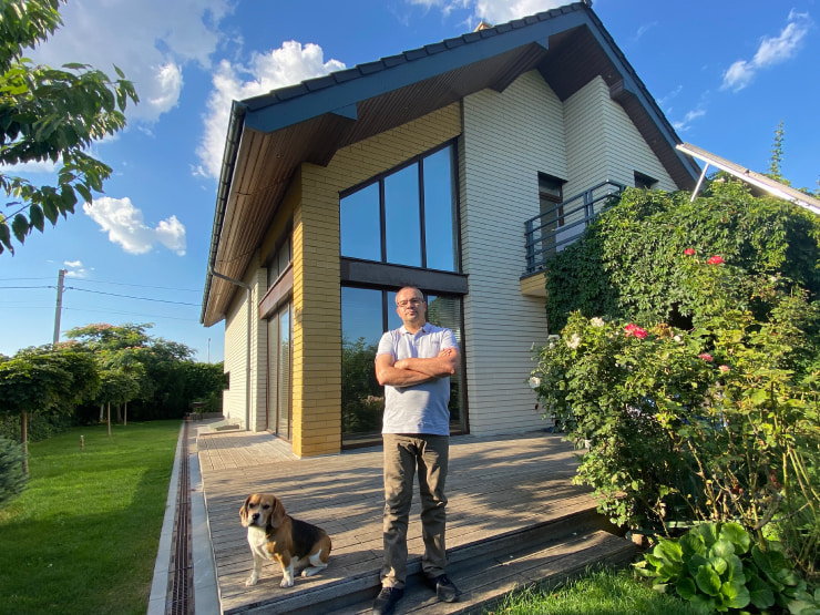 Dmytro Yunchyk with his dog Charlie next to his house, built according to the Live Home 3D project.